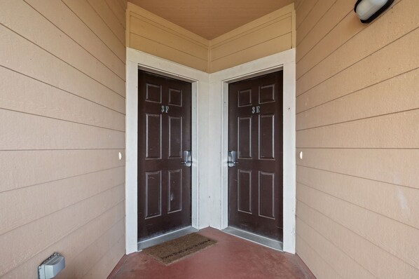 A set of double doors with numbers 3F and 3E, a doormat, and a light fixture on the wall. - Afternoon Delight-Oceanfront Condo, Pet Friendly, Community Pools (Kill Devil Hills)