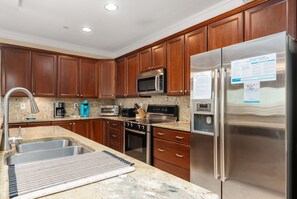 A modern kitchen with wooden cabinets, stainless steel appliances, and a granite countertop.