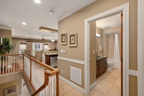 A spacious living area with a high ceiling, a staircase, and a view to a balcony. - Afternoon Delight-Oceanfront Condo, Pet Friendly, Community Pools (Kill Devil Hills)