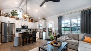 A modern kitchen with white cabinets, stainless steel appliances, and a dining area with dark chairs.