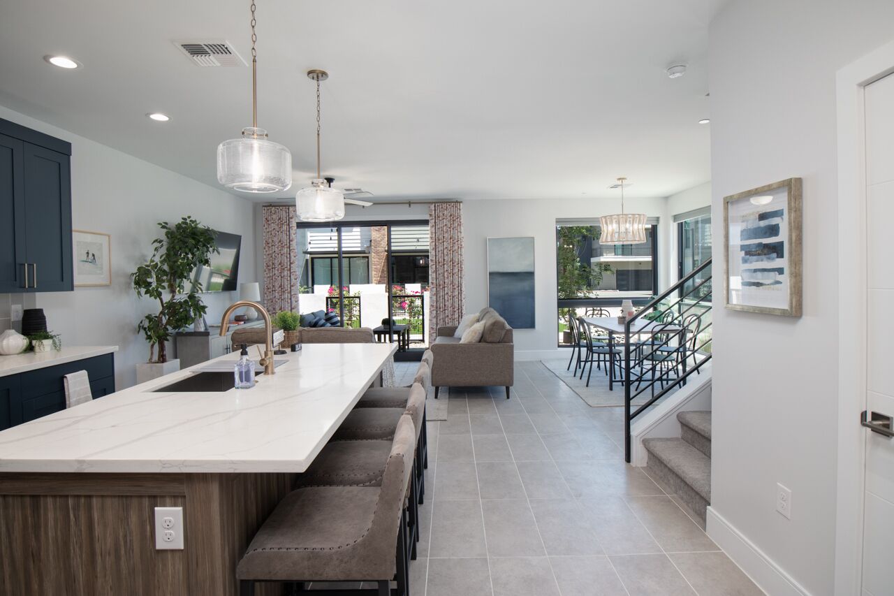 A modern kitchen with a central island, dark cabinets, and pendant lighting.