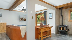 A cozy living room with a curved leather sofa, a wooden coffee table, a fireplace, and a ceiling fan. - Deck with Private Hot Tub - Updated Townhome Overlooking Gore Creek + Parking for 4 (Vail)