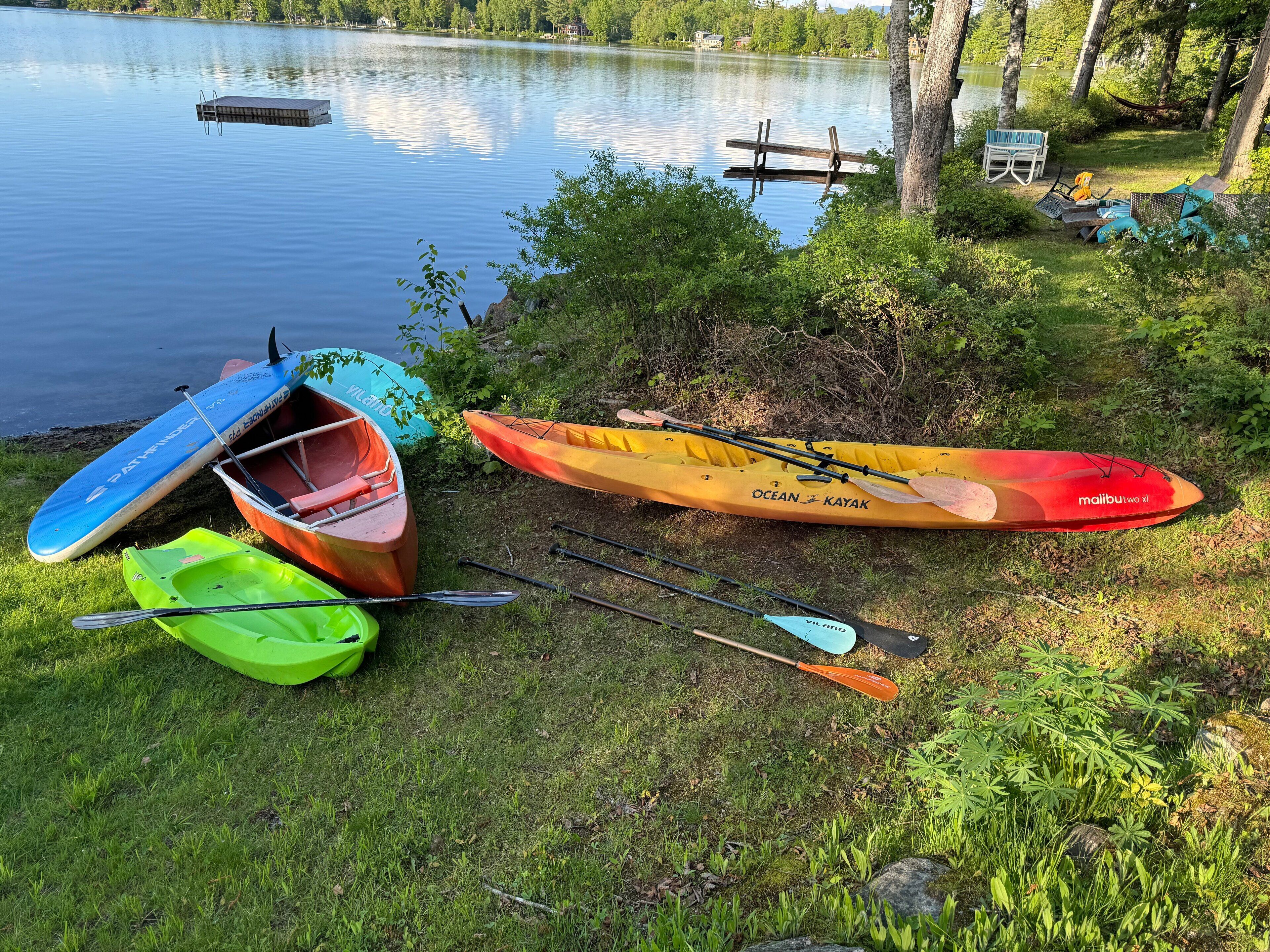 En vacker plats vid sjön med kajaker och SUP-brädor, en brygga och en hängmatta.