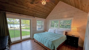 Un dormitorio con cama, ventilador de techo, ventana y vistas al exterior.
