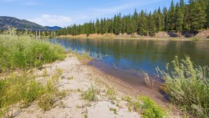 A river with a bridge, surrounded by greenery and mountains. - Clark Fork Crossing - Adventures You Seek in Western Montana.  River access.  (Superior)