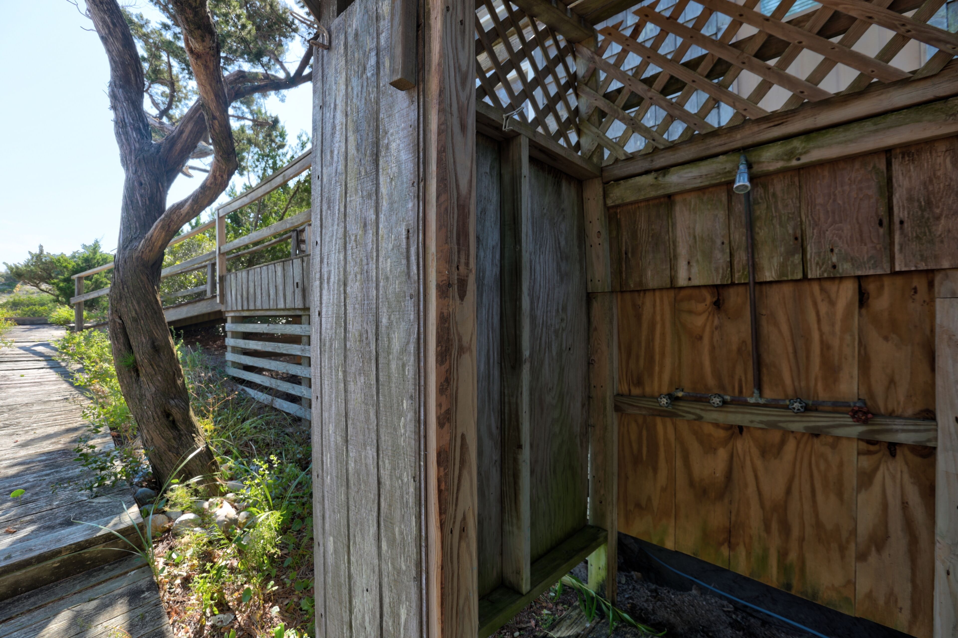 A wooden structure with a lattice roof, a wooden deck, and a tree.