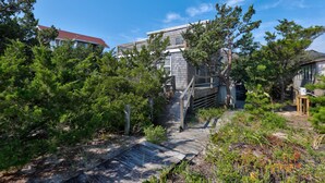 A wooden pathway leading to a house surrounded by dense greenery and trees. - Oceanfront, Amazing Sunrises, Dog Friendly, Private deck & Screened in Porch (Avon)