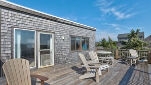 A wooden deck with Adirondack chairs and a table, overlooking a residential area. - Oceanfront, Amazing Sunrises, Dog Friendly, Private deck & Screened in Porch (Avon)