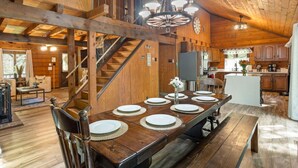 A wooden interior with a dining table set for six, a staircase, and a kitchen area. - Rustic Luxury - Log Cabin in the Pocono Mountains - Indoor Sauna- Close to Ski (Pocono Lake)