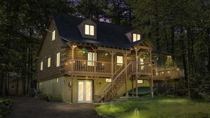A two-story wooden house with a balcony, a staircase, and a door. - Rustic Luxury - Log Cabin in the Pocono Mountains - Indoor Sauna- Close to Ski (Pocono Lake)