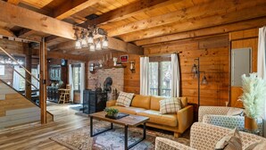 A cozy cabin interior with a wooden interior, a sofa, patterned chairs, a coffee table, and a fireplace. - Rustic Luxury - Log Cabin in the Pocono Mountains - Indoor Sauna- Close to Ski (Pocono Lake)