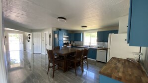 A spacious kitchen with a dining area, featuring a large wooden table and chairs, a refrigerator, and a microwave. - Blue Mountain Retreat (Elgin)