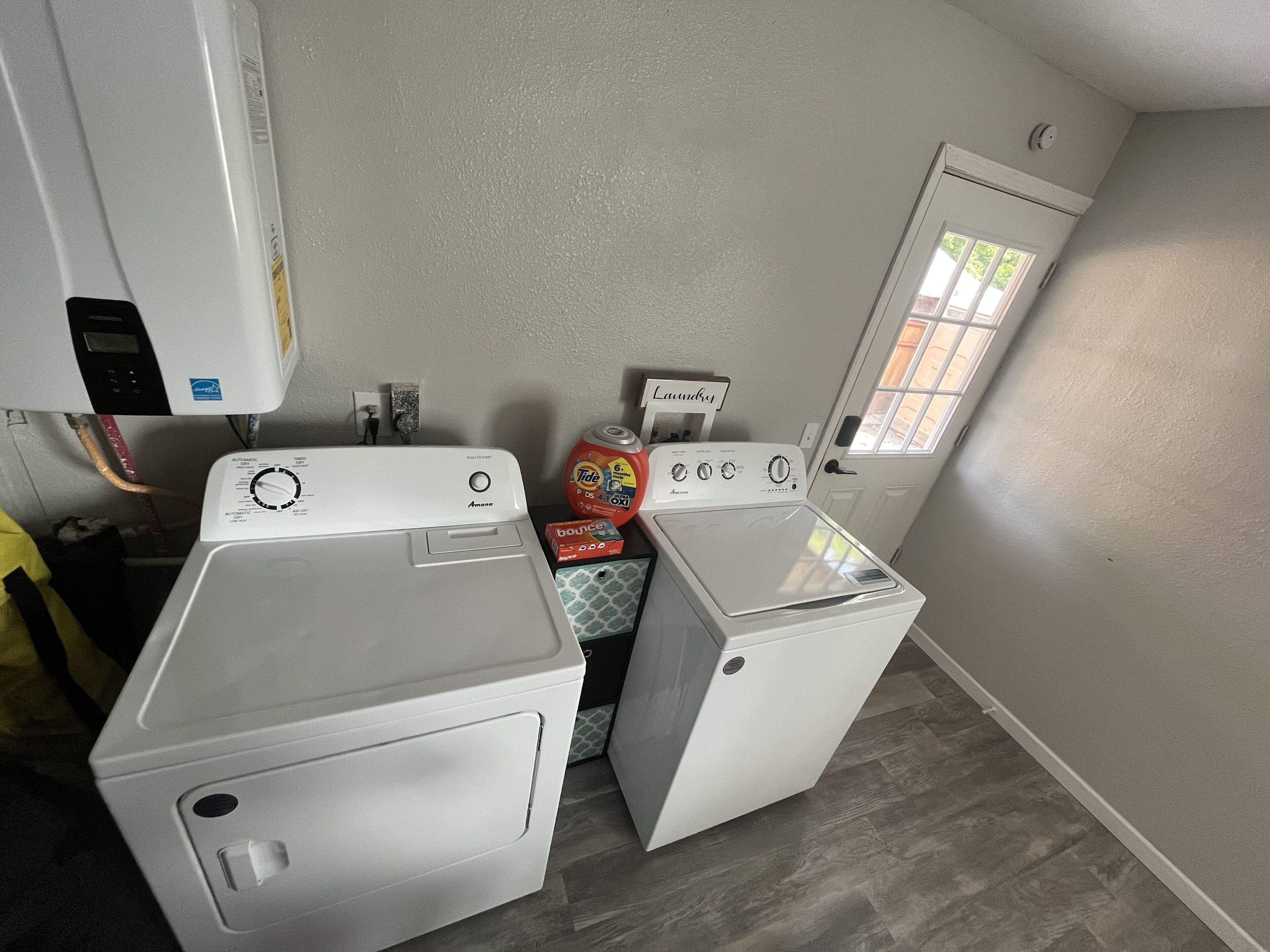 A laundry room with two front-loading washing machines, a dryer, and a small window.
