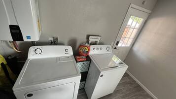 A laundry room with two front-loading washing machines, a dryer, and a small window.