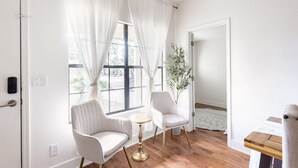 Una habitación con dos sillones blancos, una mesita redonda y una planta en maceta.