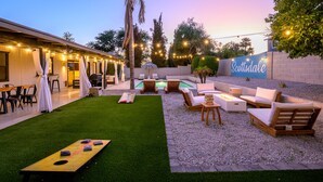 Un patio trasero con piscina, mobiliario exterior y un porche cubierto.