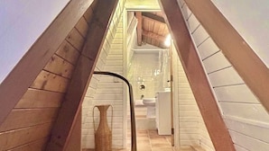 A triangular room with a wooden floor, a small table, and a bench.