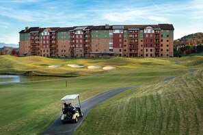Un terrain de golf avec un club-house et un immeuble à plusieurs étages en arrière-plan.