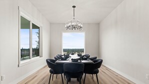 A dining room with a large table set for six, a chandelier, and a view through a large window. - Spokane Dream (Spokane County)