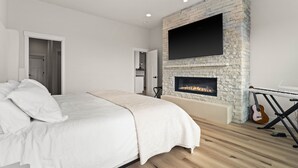 A bedroom with a bed, a fireplace, a television, and a guitar. - Spokane Dream (Spokane County)