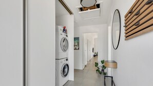 A laundry room with a washing machine, a mirror, and a lamp. - New and modern holiday home with hot tub (Frørup)