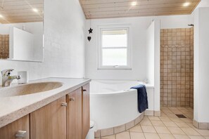 A modern bathroom with a freestanding bathtub, a large mirror, and a shower area with tiled walls.