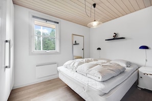 A bedroom with a bed, a window, a radiator, a ceiling fan, and a nightstand.