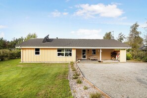 A single-story building with a sloped roof, a front porch, and a gravel driveway.