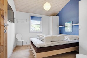 A bedroom with a bed, a chair, a window, and a door.
