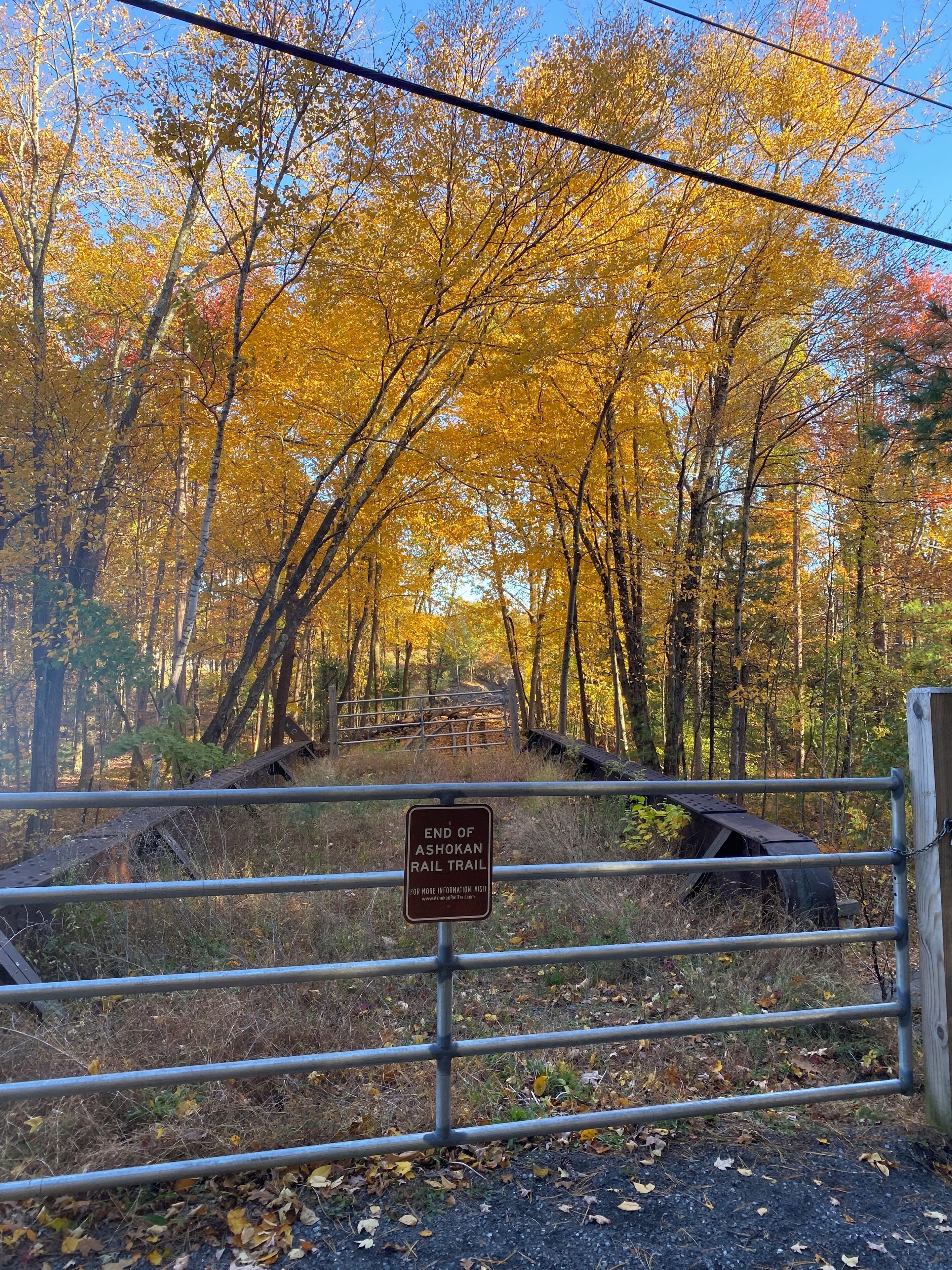 Una reja metálica con un letrero que indica el final del Ashokan Rail Trail.