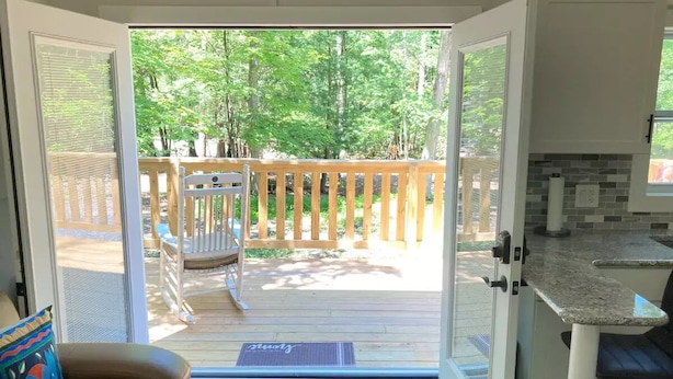 A view from a room with a sliding glass door leading to an outdoor deck with a wooden fence, a chair, and a bench.