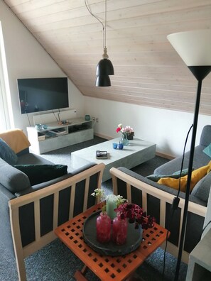 Ett modernt vardagsrum med en platt-TV, ett soffbord och en soffa.