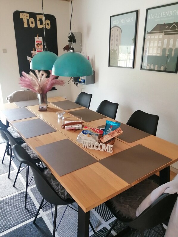 Une salle de conférence avec un panneau indiquant les tâches à accomplir, un panneau de bienvenue et des photos encadrées accrochées au mur.