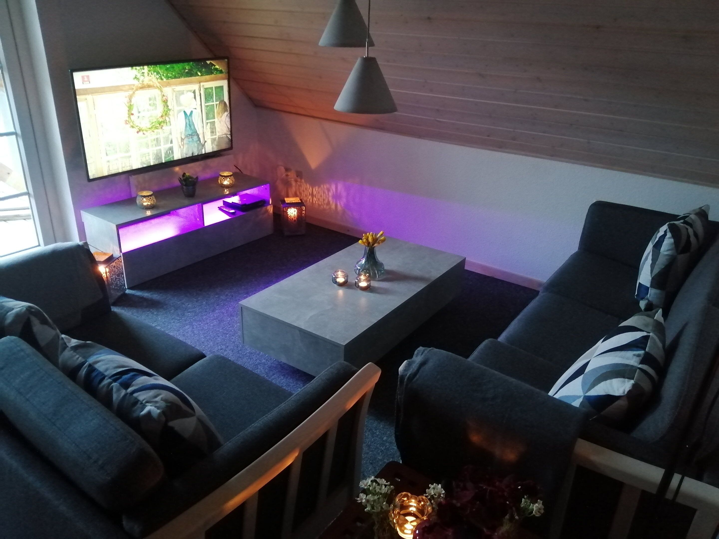 Ein modernes Wohnzimmer mit einer Couch, einem Couchtisch und einem an der Wand befestigten Fernseher.