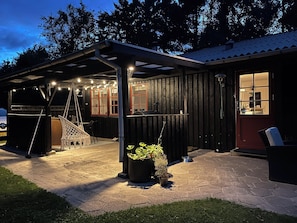 A covered outdoor area with a grill, seating, and potted plants. - Lovely house in scenic Thy (Thyholm)