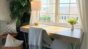 Un bureau d’angle avec une lampe, une plante en pot et une vue par la fenêtre.