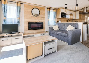 A compact living space with a TV, sofa, kitchen area, and a mirror.