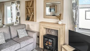 A living room with a sofa, fireplace, television, and a mirror.