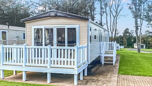 A mobile home with a porch, a small deck, and a paved walkway.