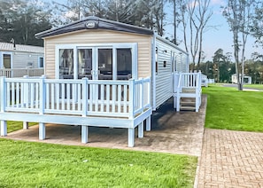 Ein Wohnmobil mit Veranda, einer kleinen Terrasse und einem gepflasterten Weg.