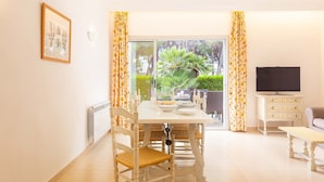 A dining area with a table set for two, a television, and a sofa. - Nice apartment near the beach in Port de Pollença (Port de Pollença)