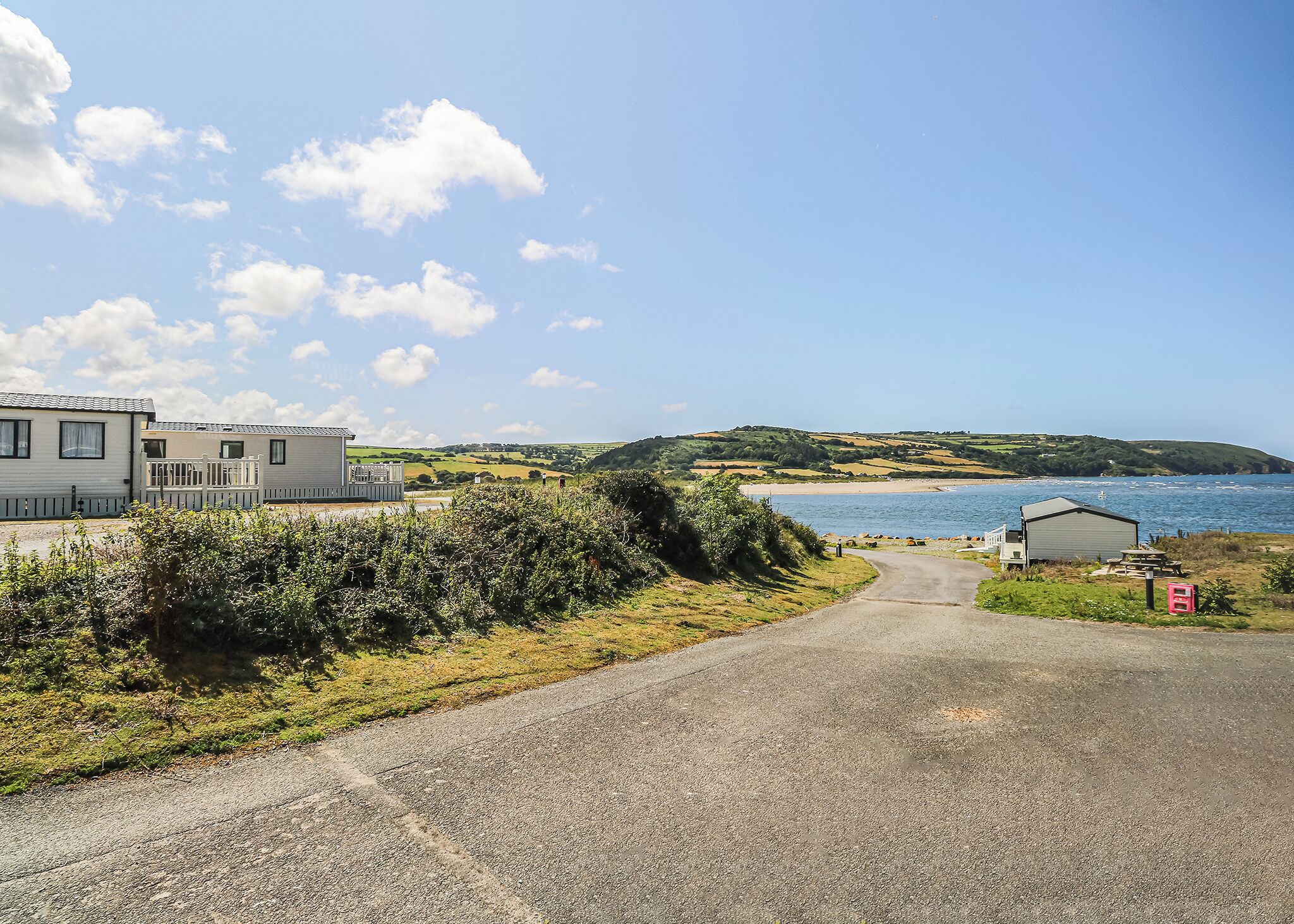 Eine Küstenstraße führt zu einem Caravanpark mit Blick auf den Strand.