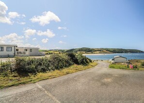 A coastal road leading to a caravan park with a beach view. - Large 12ft-wide caravan with one double with en suite W. (Cardigan)