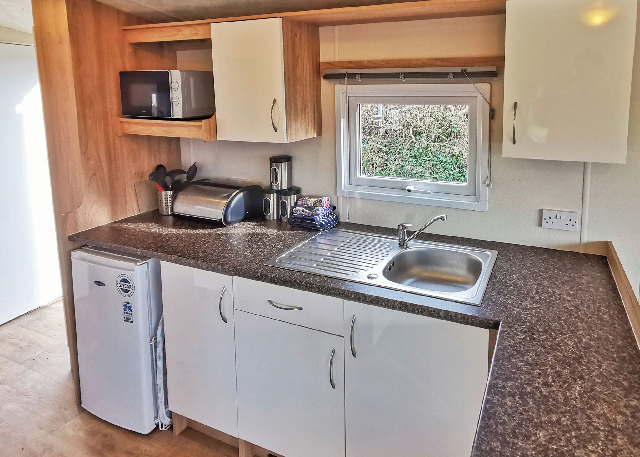 A compact kitchenette with a sink, a microwave, a toaster, and a small refrigerator.