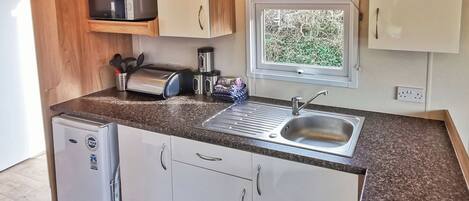 A compact kitchenette with a sink, a microwave, a toaster, and a small refrigerator.