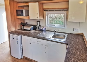 A compact kitchenette with a sink, a microwave, a toaster, and a small refrigerator.
