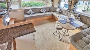 A cozy RV interior with a dining area, seating, and a kitchen. - Spacious and well presented 12ft wide caravan with one double and two twin. (Ludchurch, Nr Saundersfoot)