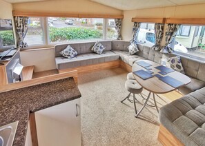 Un interior de autocaravana acogedor, con comedor, asientos y cocina.