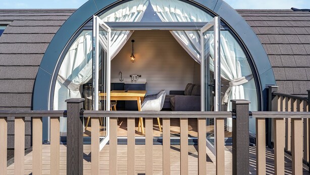 Een gezellige, halfopen ruimte met een houten tafel, een bank en een klein keukentje.