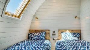 Een kamer met twee bedden, een dakraam en een wandlamp.